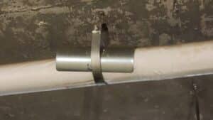 Metal clamp securing a pipe to wall