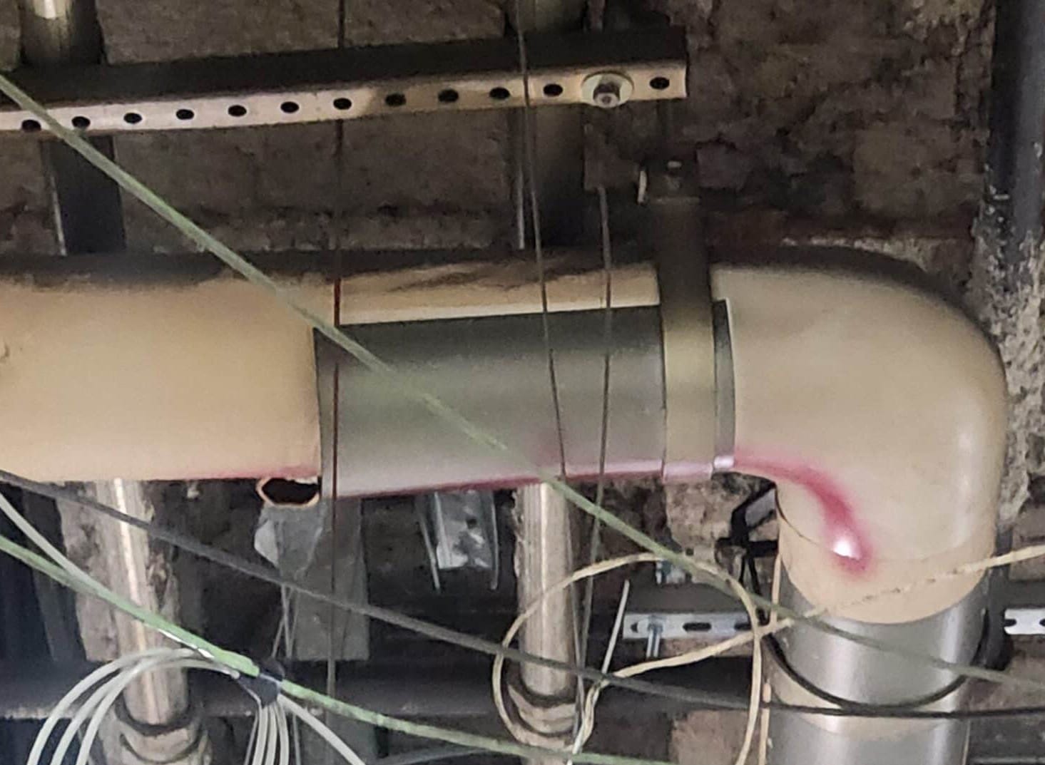 Exposed pipes and wires on ceiling structure.